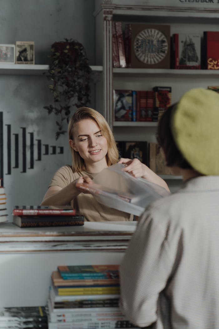 A cheerful female clerk helps a customer at a cozy bookstore counter.